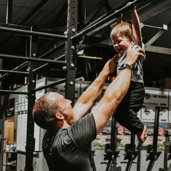 father-lifting-child-pull-up-bar-gym